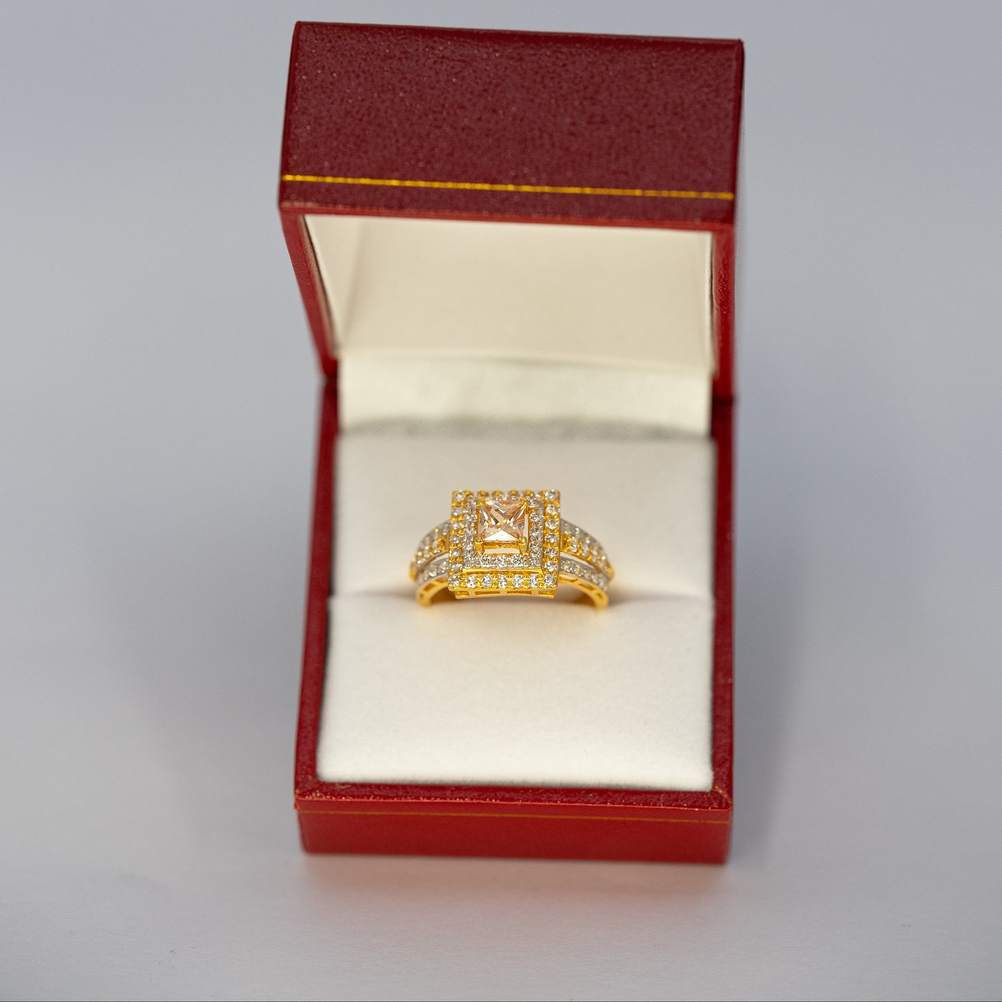 Gold ring in a red jewelry box on a light gray background