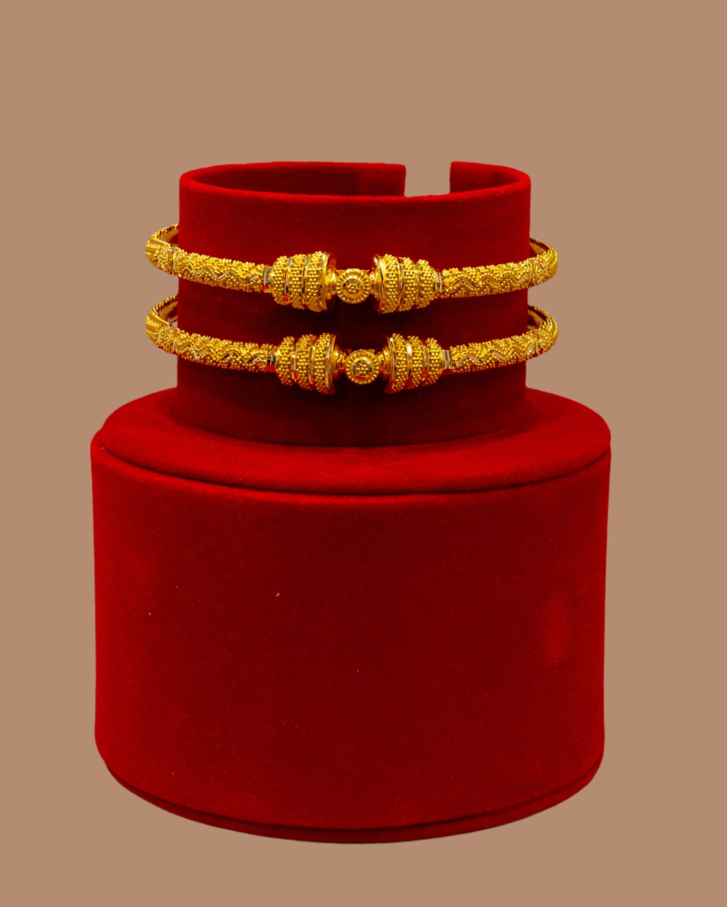Red velvet box with gold bracelets on a beige background