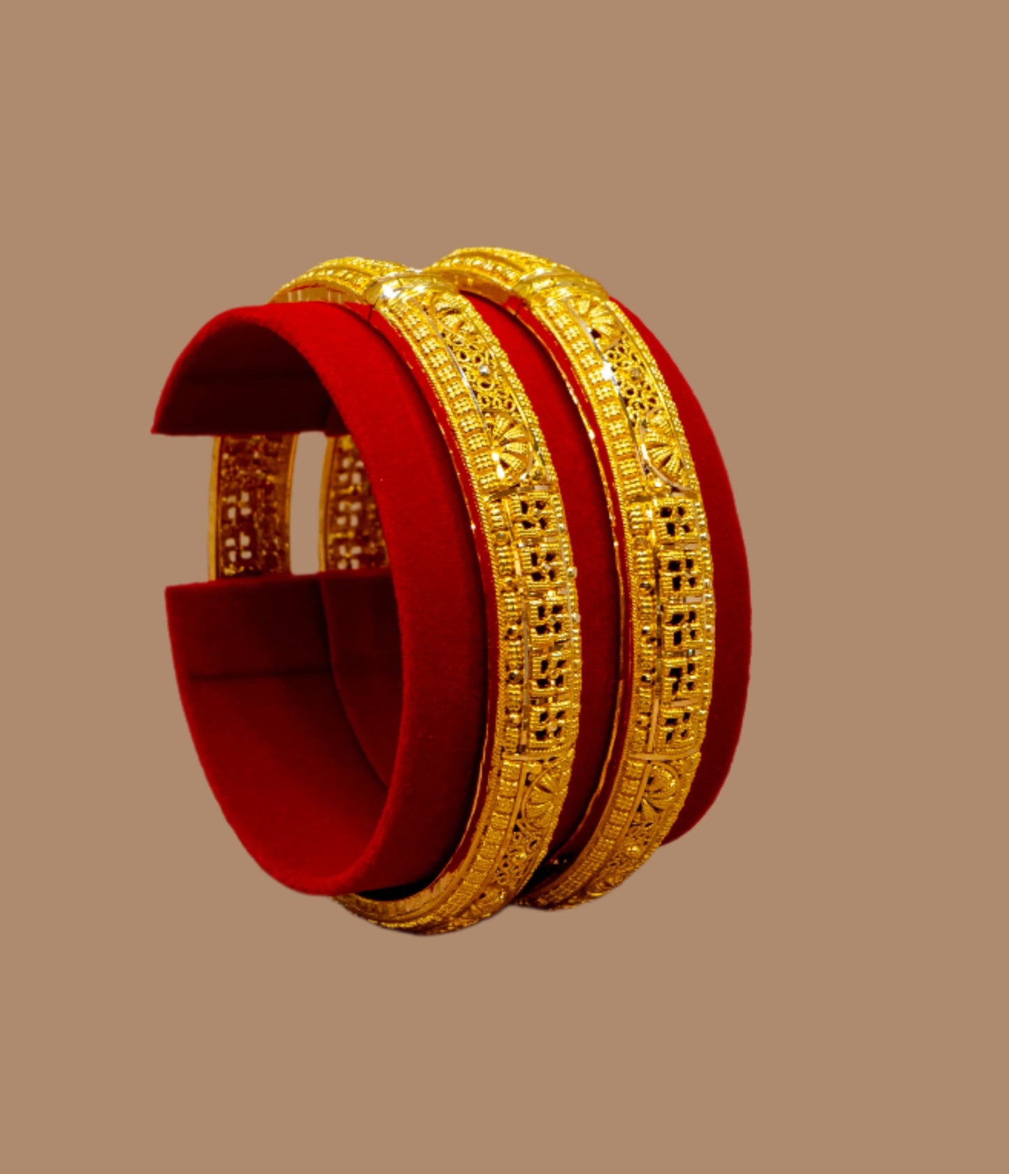 Two gold bangles on a red stand against a beige background