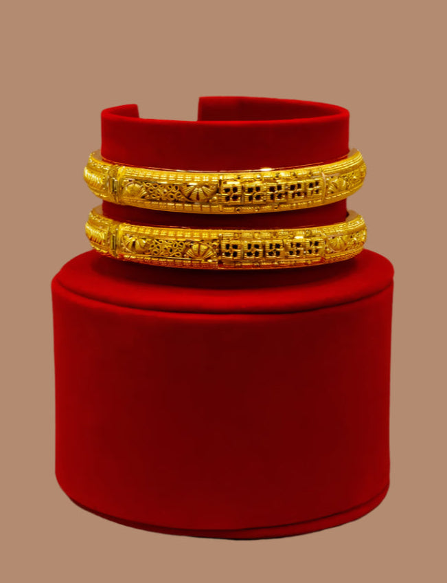 Gold bracelets on a red velvet stand against a beige background