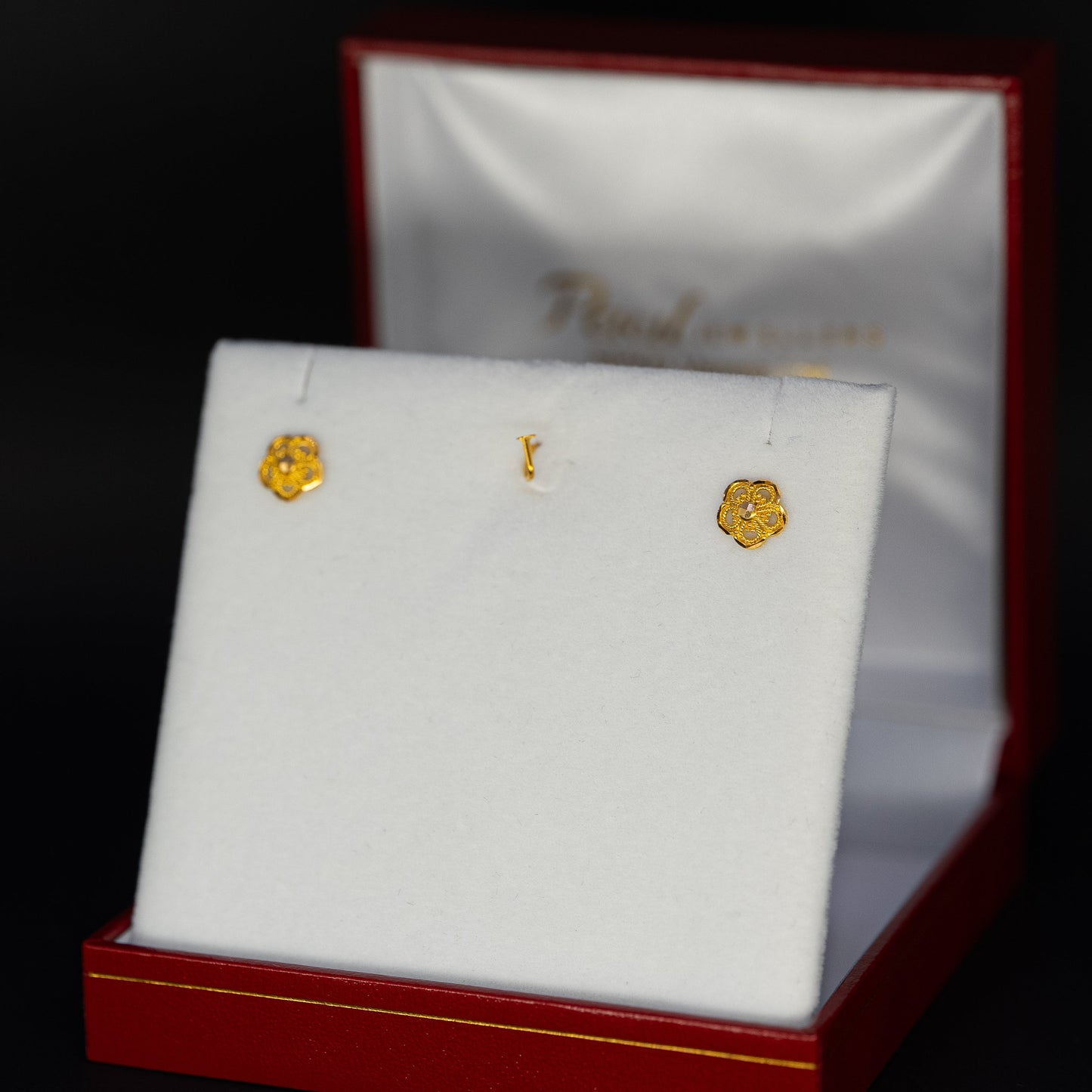 Gold earrings in a jewelry box with a dark background