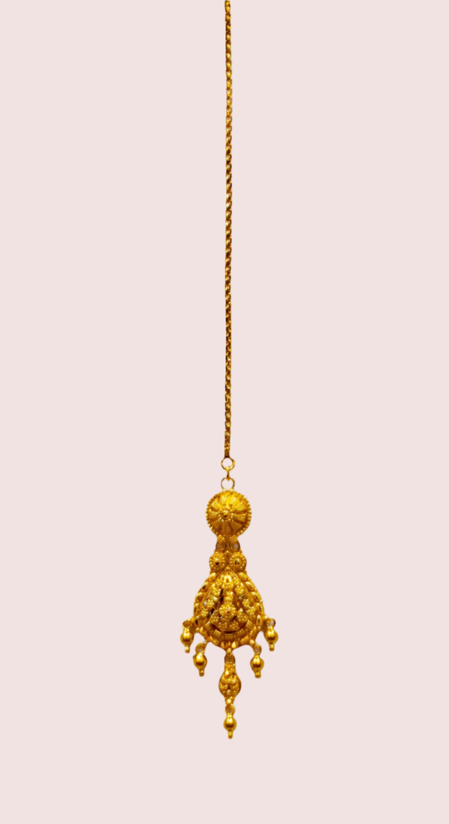 Gold tikka with a decorative pendant on a white background