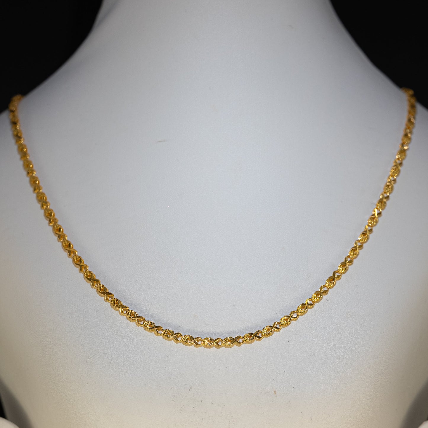 Gold necklace on a mannequin with a plain background