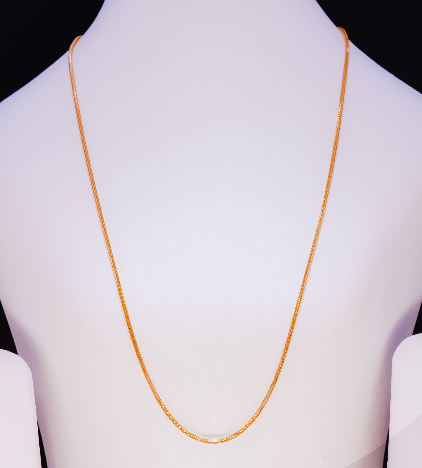 Gold necklace on a mannequin with a plain background