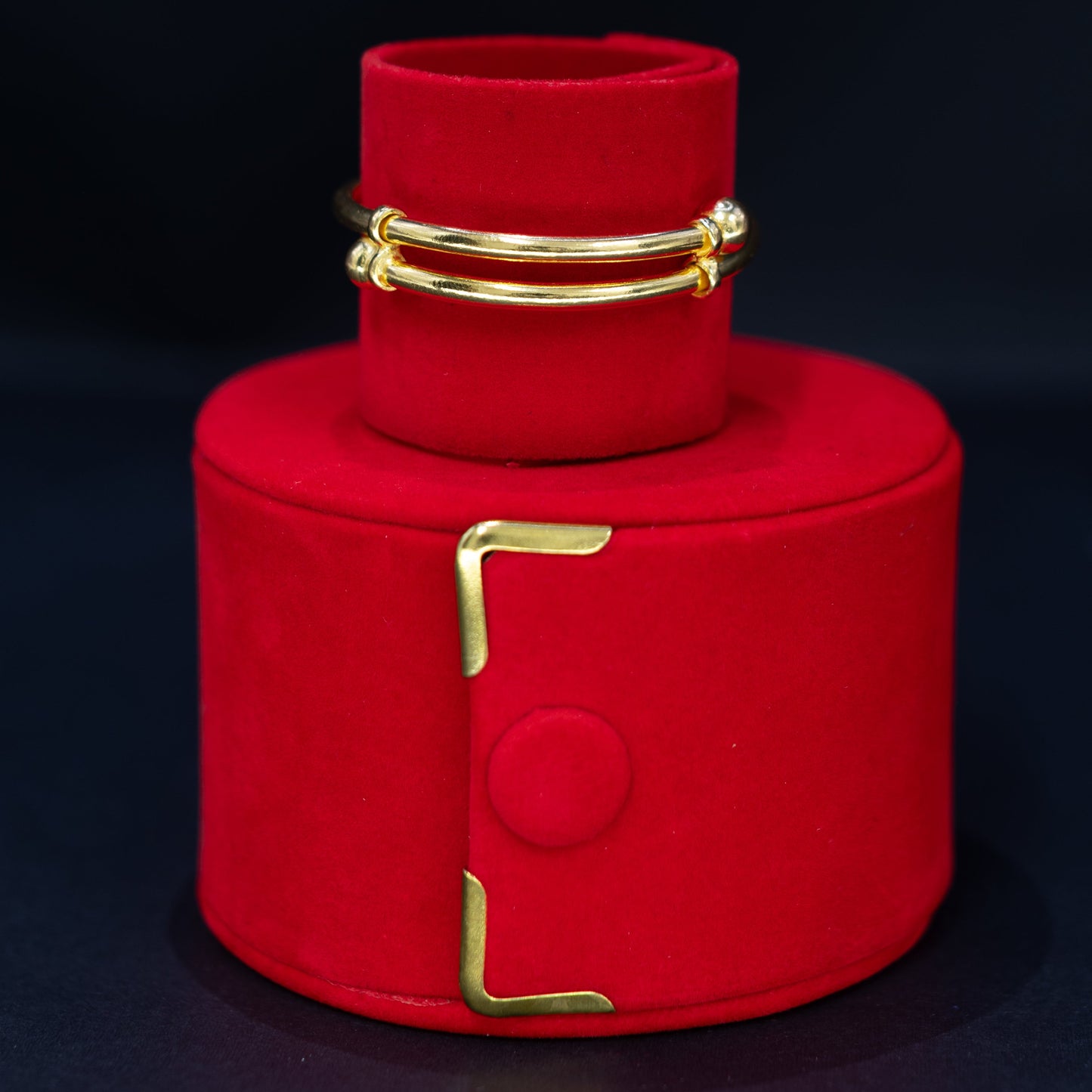 A adjustable baby bracelet displayed on a red cylindrical jewelry stand against a dark background.