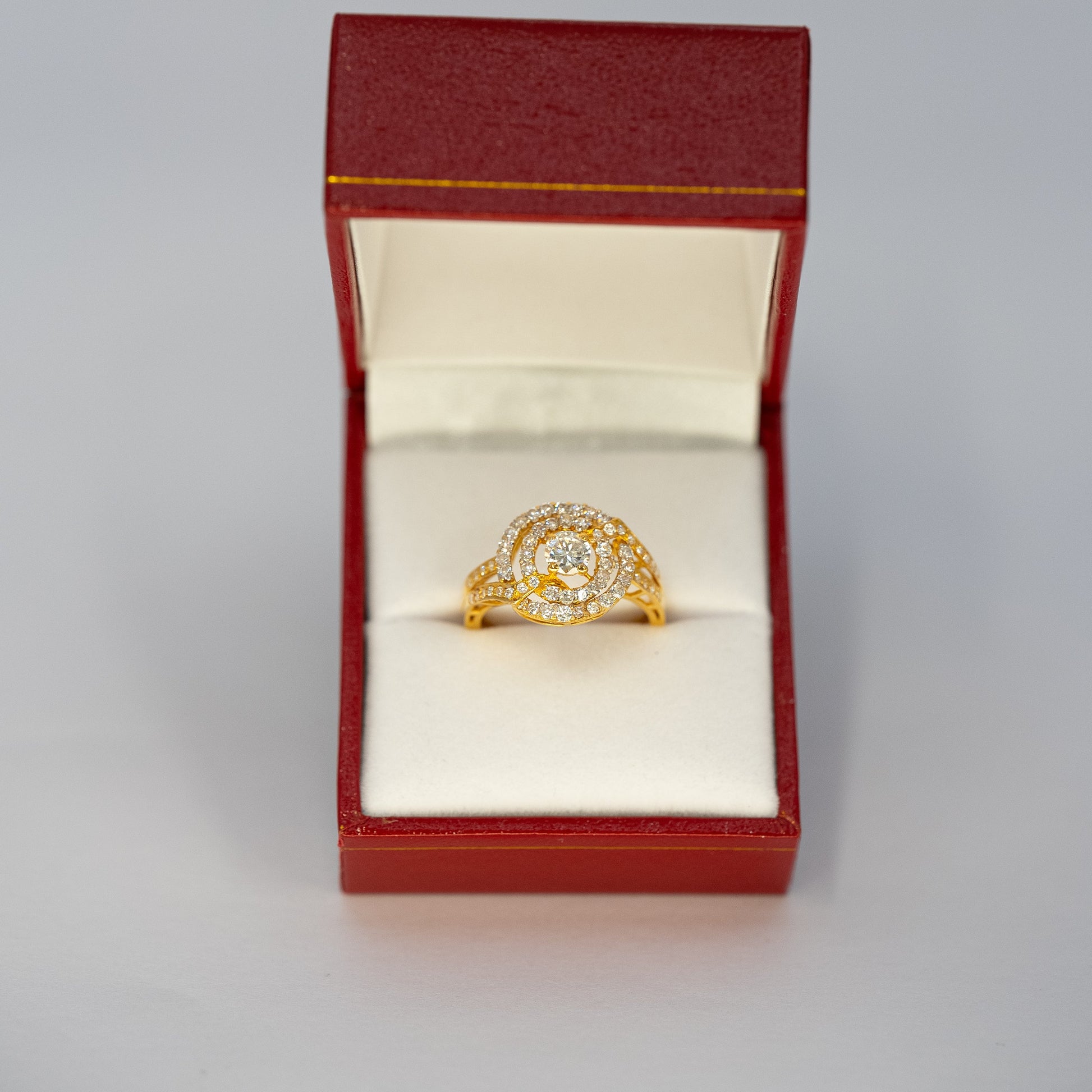Gold ring with a diamond in an open red jewelry box on a light gray background
