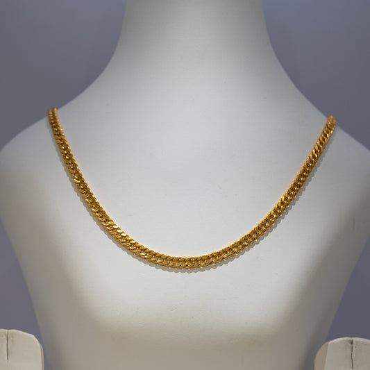 Gold chain necklace on a mannequin bust against a gray background