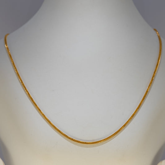 Gold necklace on a mannequin against a gray background