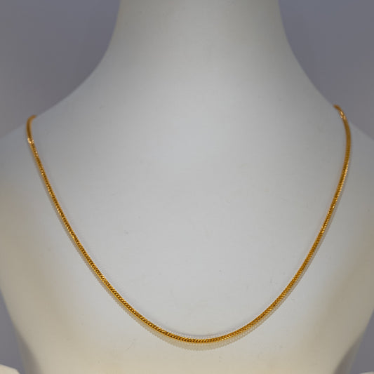 Gold necklace on a mannequin against a gray background
