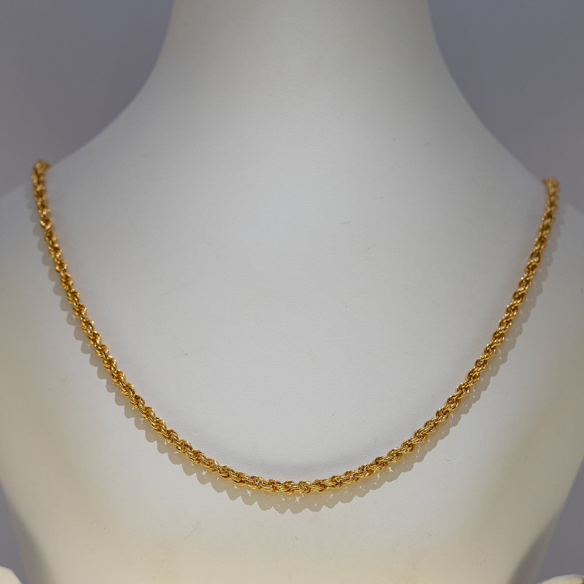 Gold necklace on a mannequin against a gray background