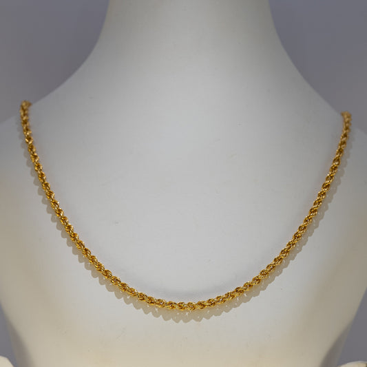 Gold necklace on a mannequin against a gray background