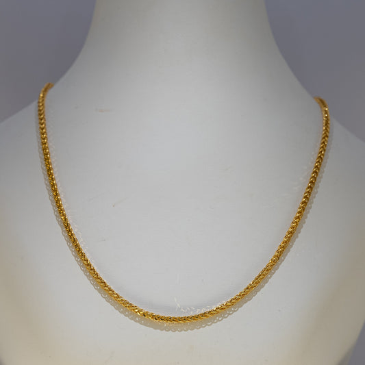 Gold necklace on a mannequin against a gray background