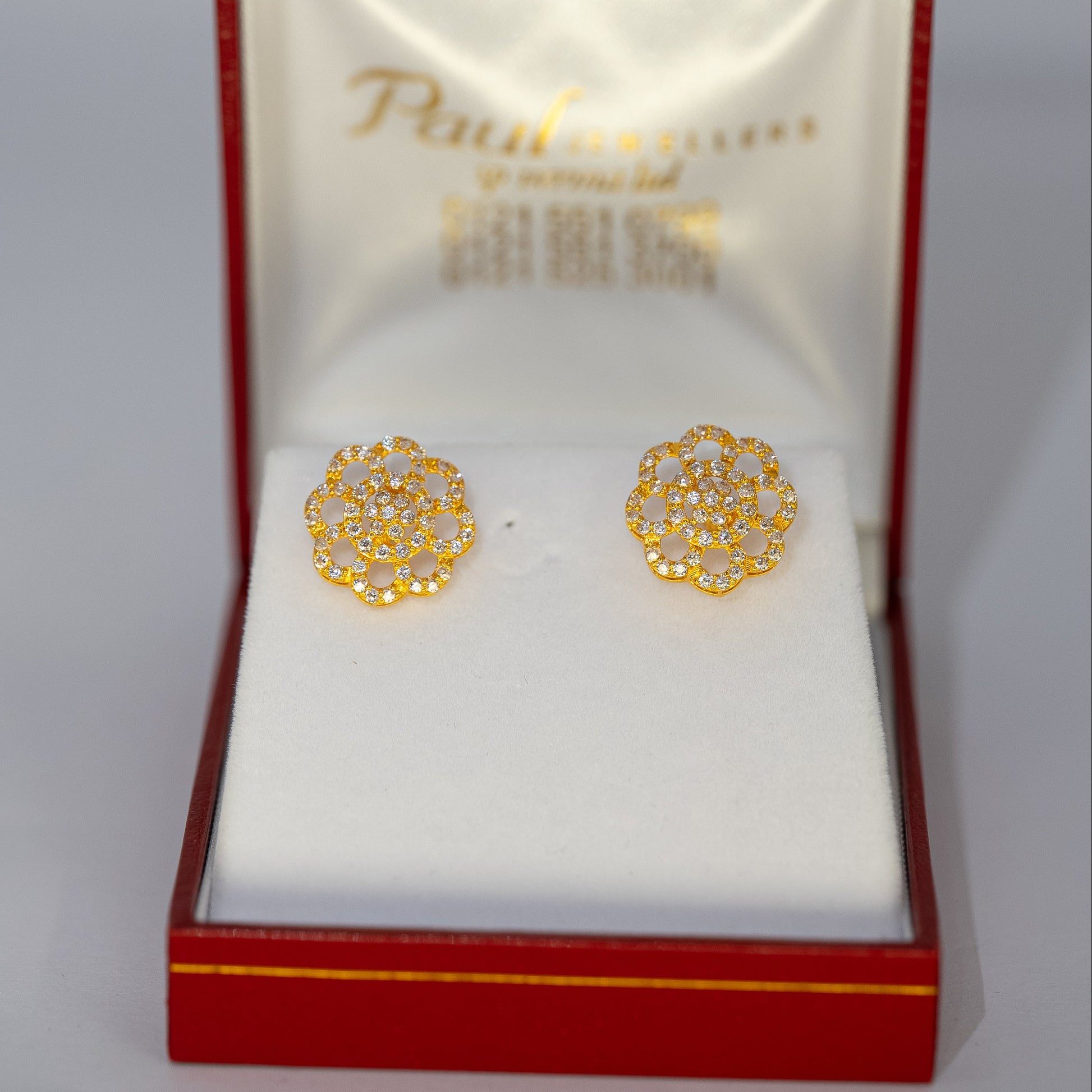 Gold earrings in a red and gold box on a white background