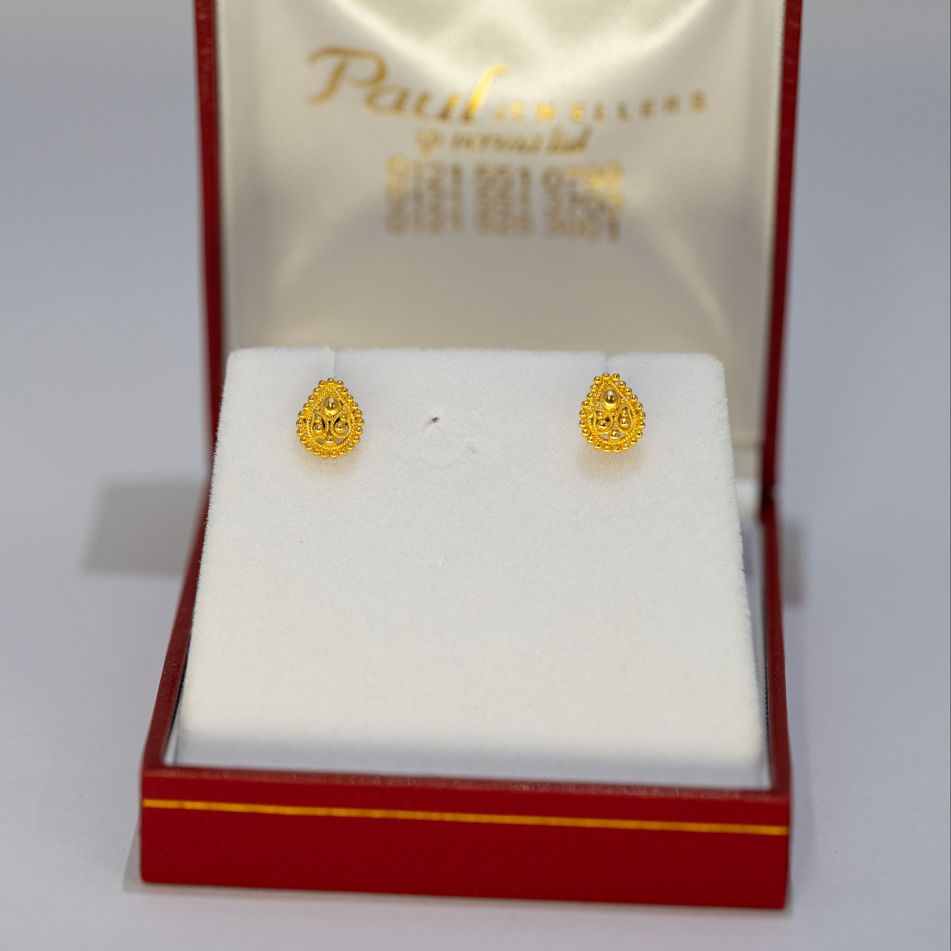 Gold earrings in a Paul Jewellers box on a white background