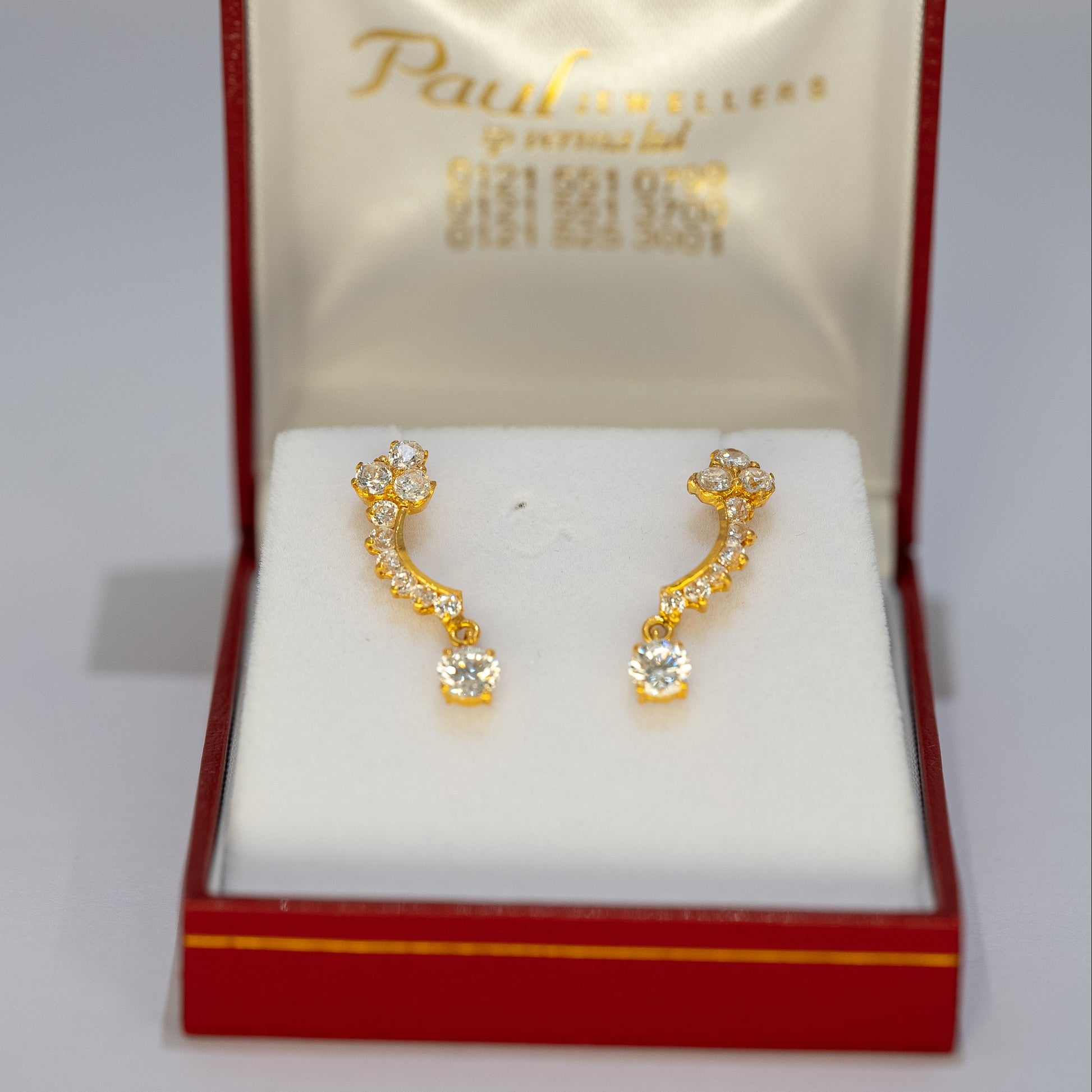 Gold earrings in a Paul Jewellers box on a white background