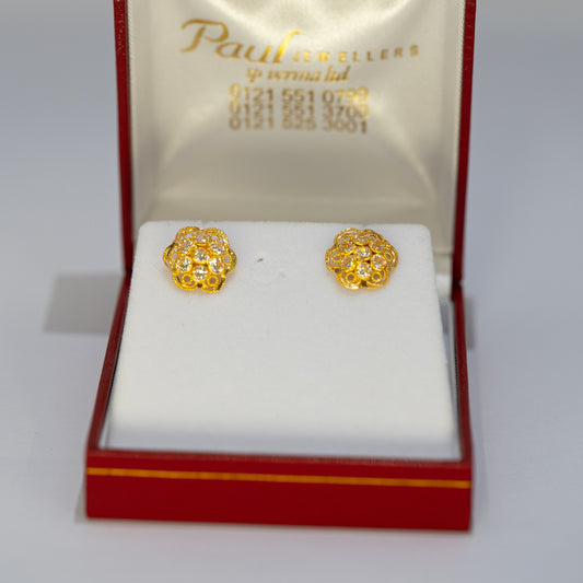 Gold earrings in a Paul's Jewels box on a gray background