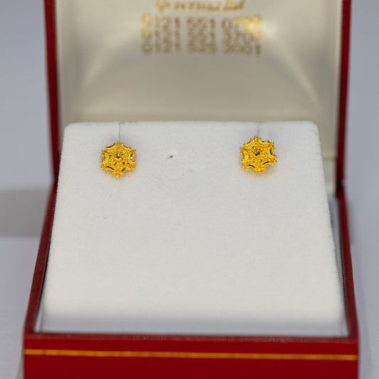 Gold earrings in a Paul jewelry box on a white background