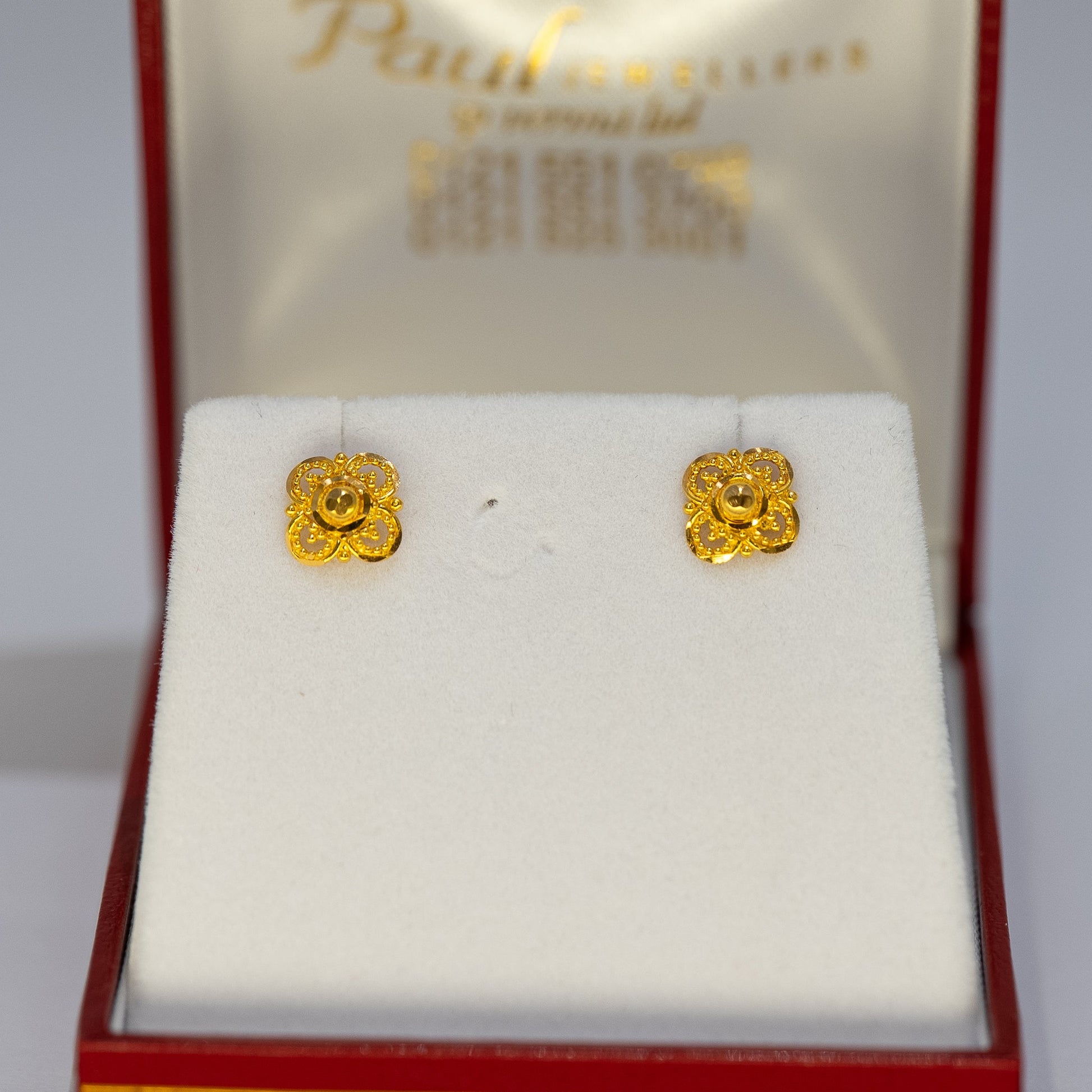 Gold earrings in a red and gold box with 'Paul' branding.