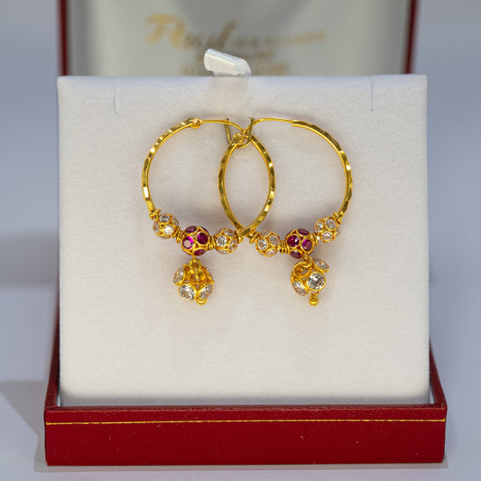 Gold earrings with gemstones in a red jewelry box