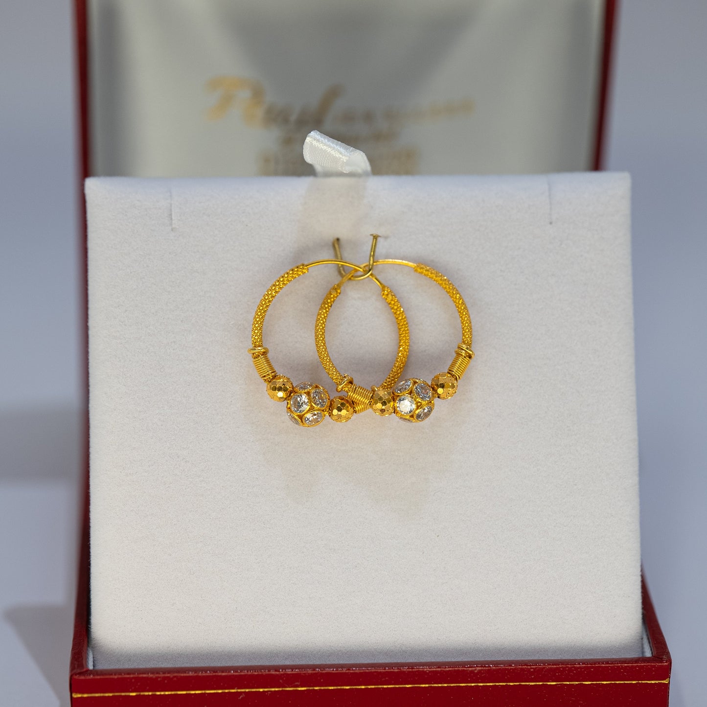 Gold hoop earrings in a red and white jewelry box