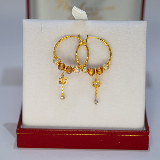 Gold hoop earrings with beads on a white cushion in a red jewelry box.