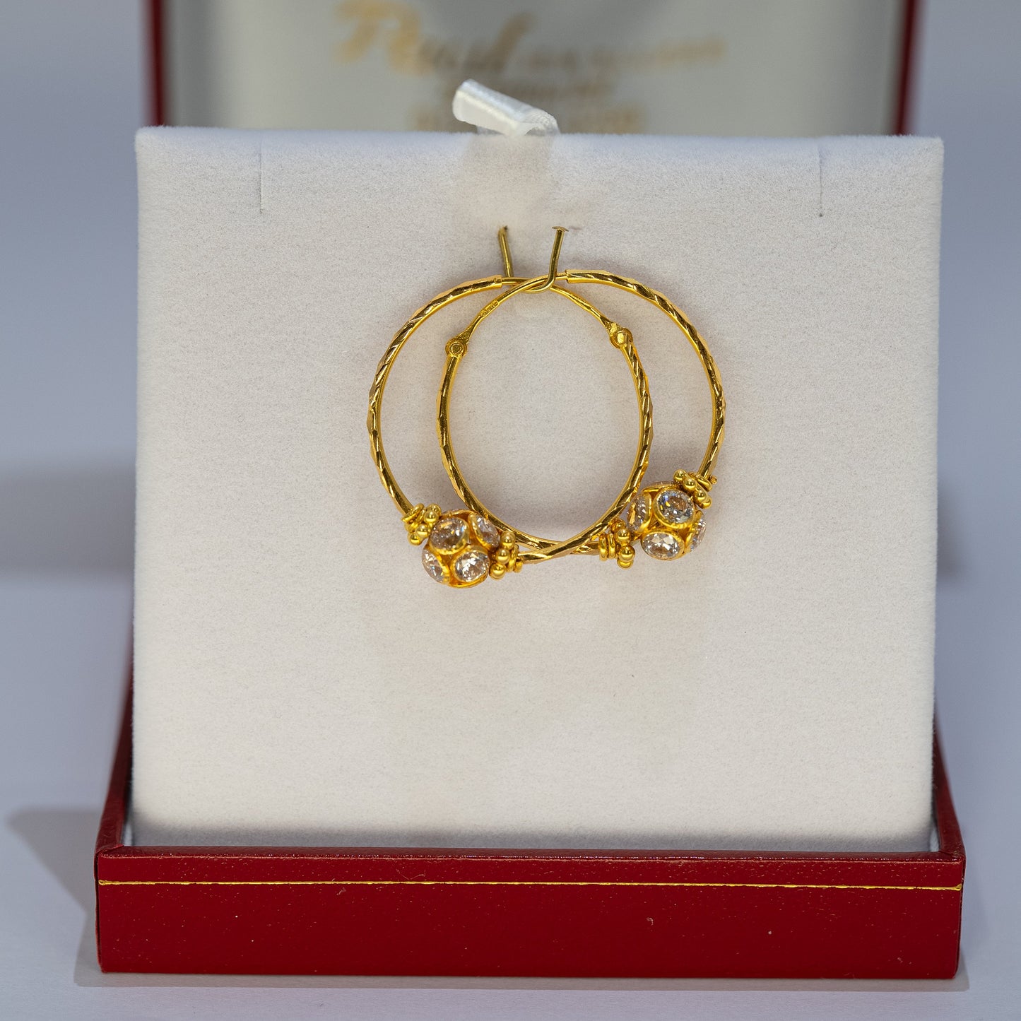 Gold hoop earrings on a white cushion in a red jewelry box