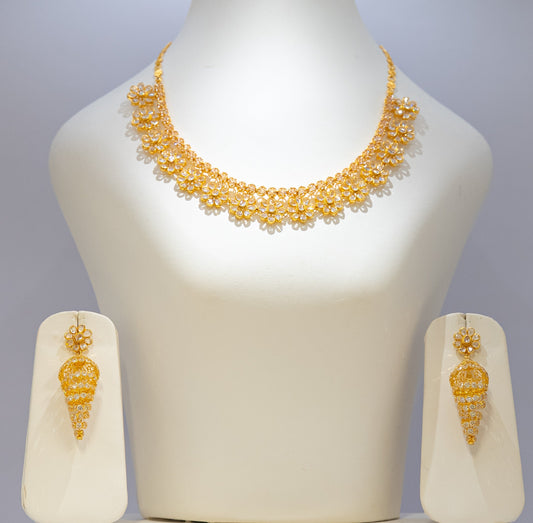 Gold necklace and earrings set on a mannequin bust with a plain background