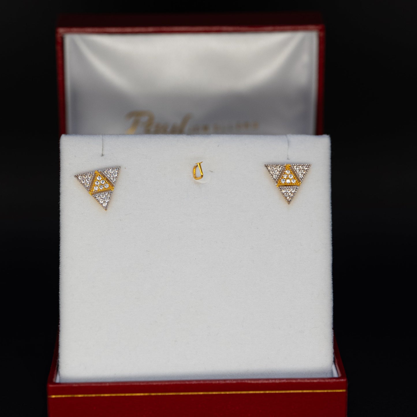 Triangular earrings in a jewelry box on a black background