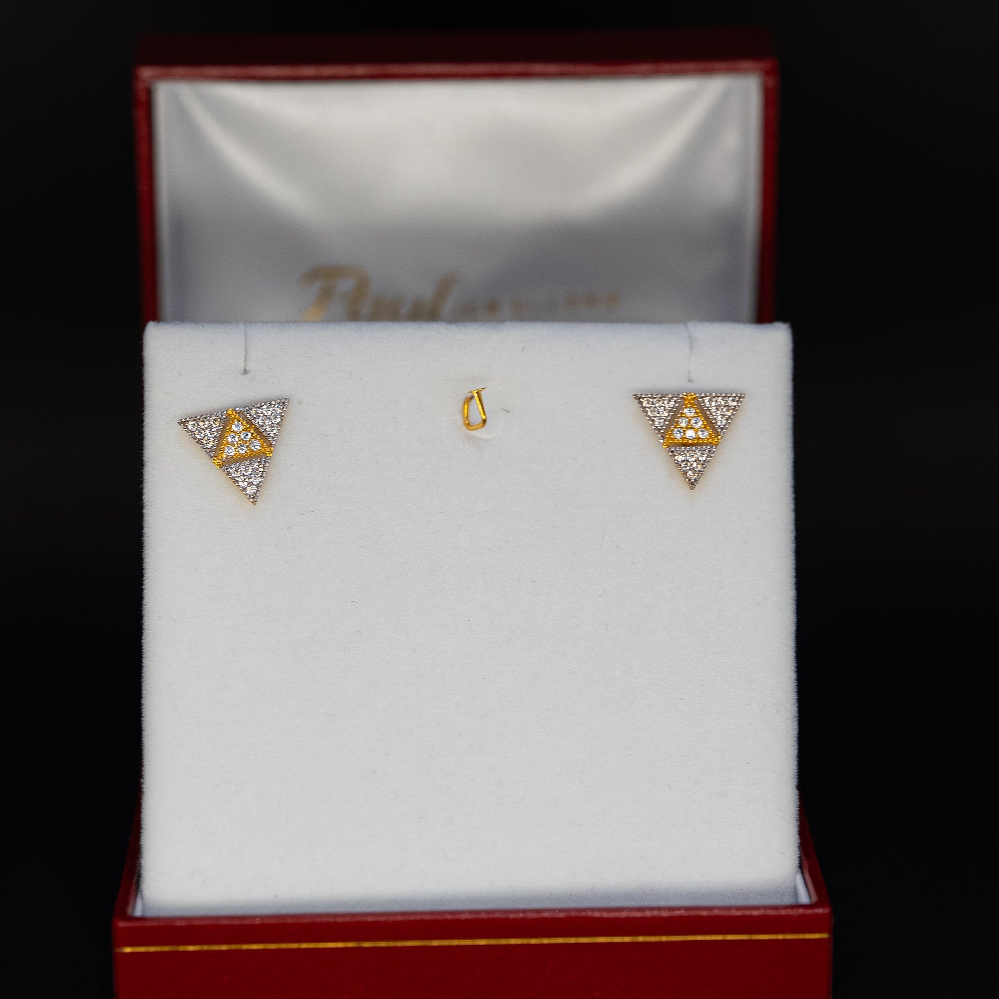Triangular earrings in a jewelry box on a black background