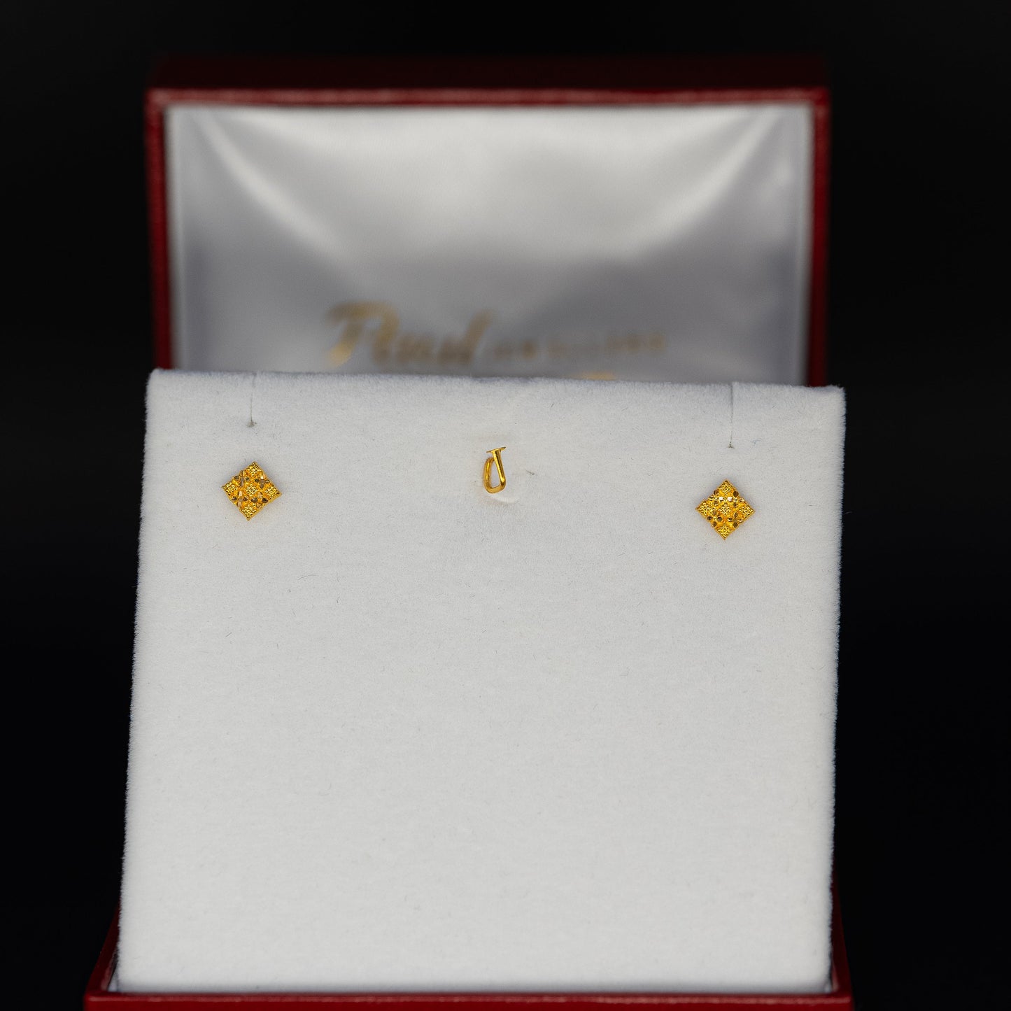 Gold earrings in a jewelry box on a black background