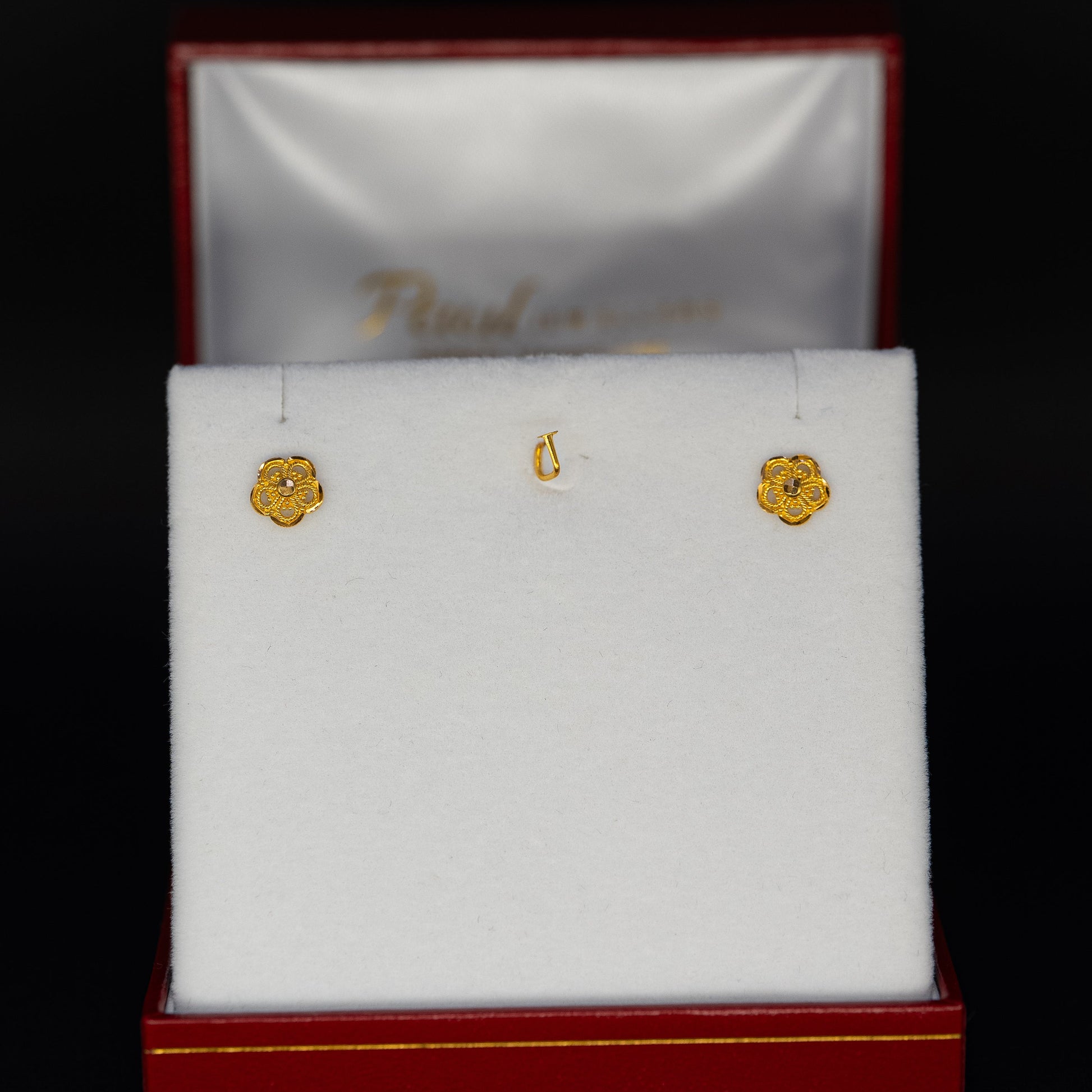 Gold earrings in a jewelry box with a black background