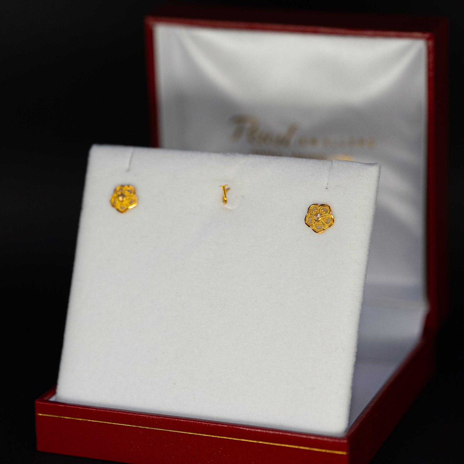 Gold earrings in a jewelry box with a dark background