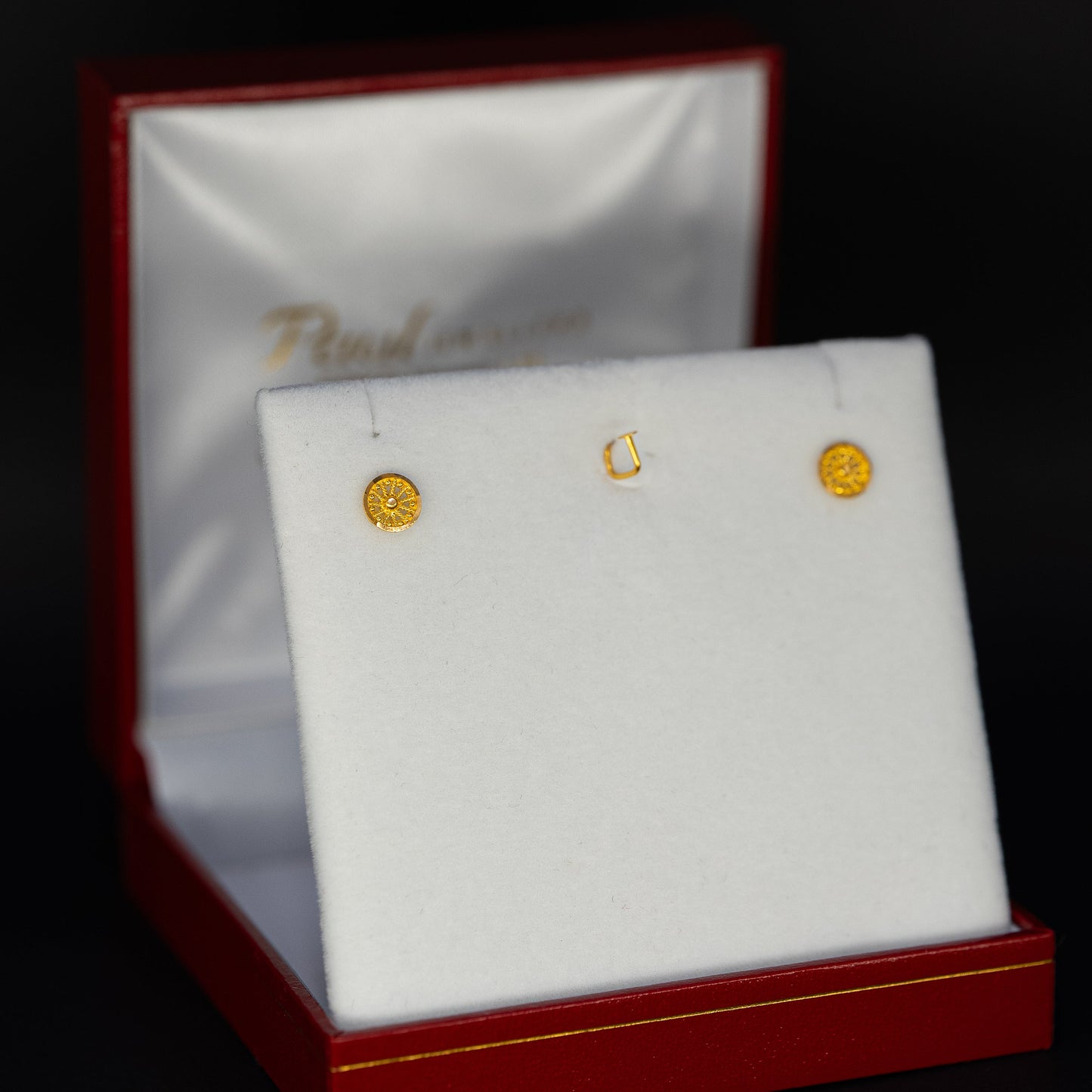 Gold earrings in a jewelry box with a dark background