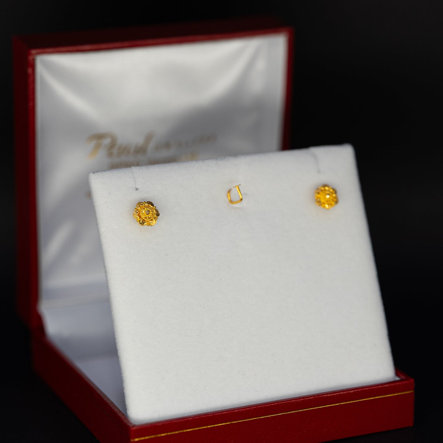 Gold earrings in a jewelry box on a black background
