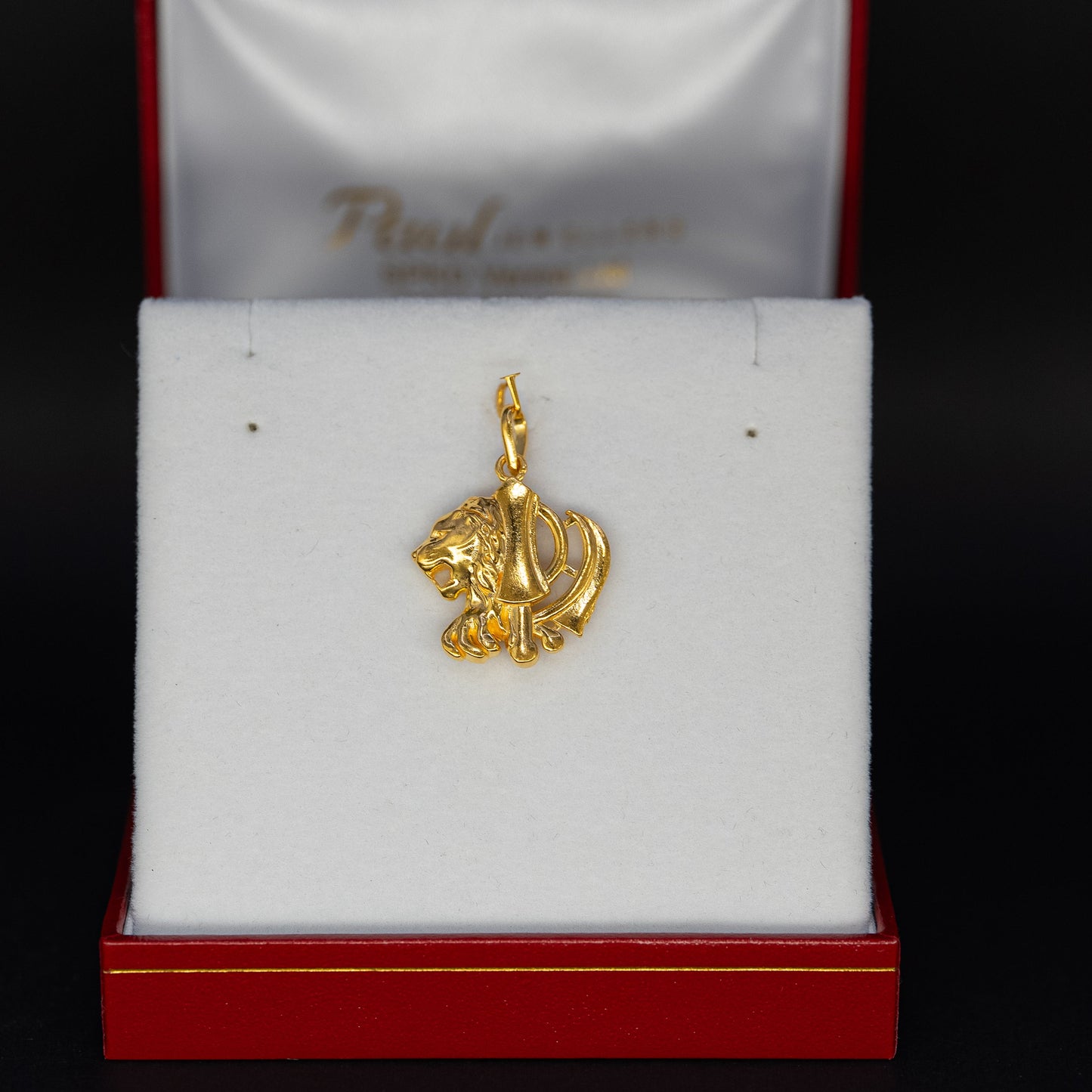Gold lion pendant in a red and white box on a black background