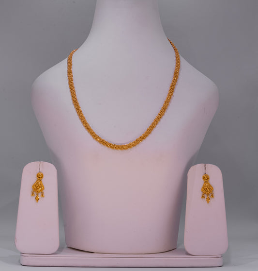 Gold necklace and earrings on a mannequin bust with pink stands against a gray background