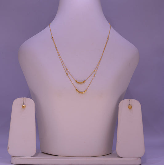 Gold necklace and earrings on a mannequin bust with a purple background