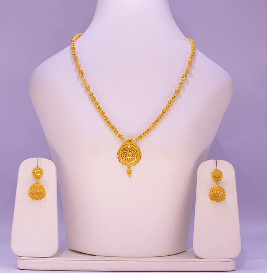 Gold necklace and earrings set on a mannequin bust with a purple background