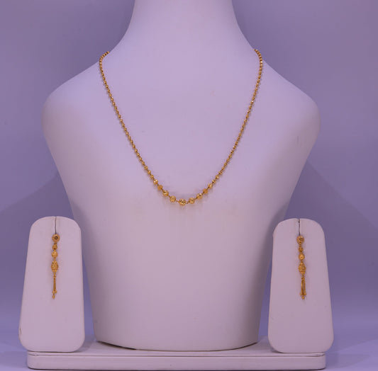 Gold necklace and earrings on a mannequin bust with a purple background