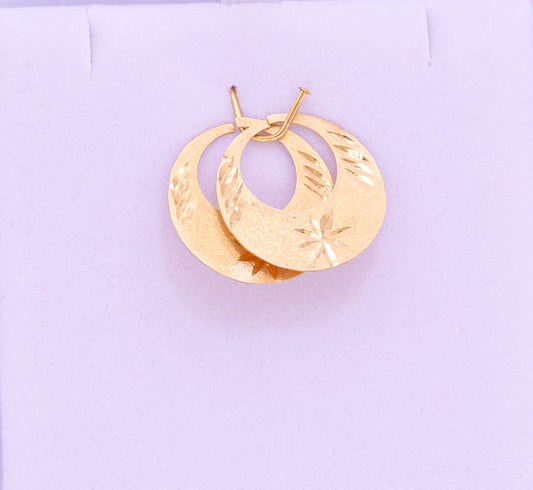 Gold hoop earrings on a light purple background