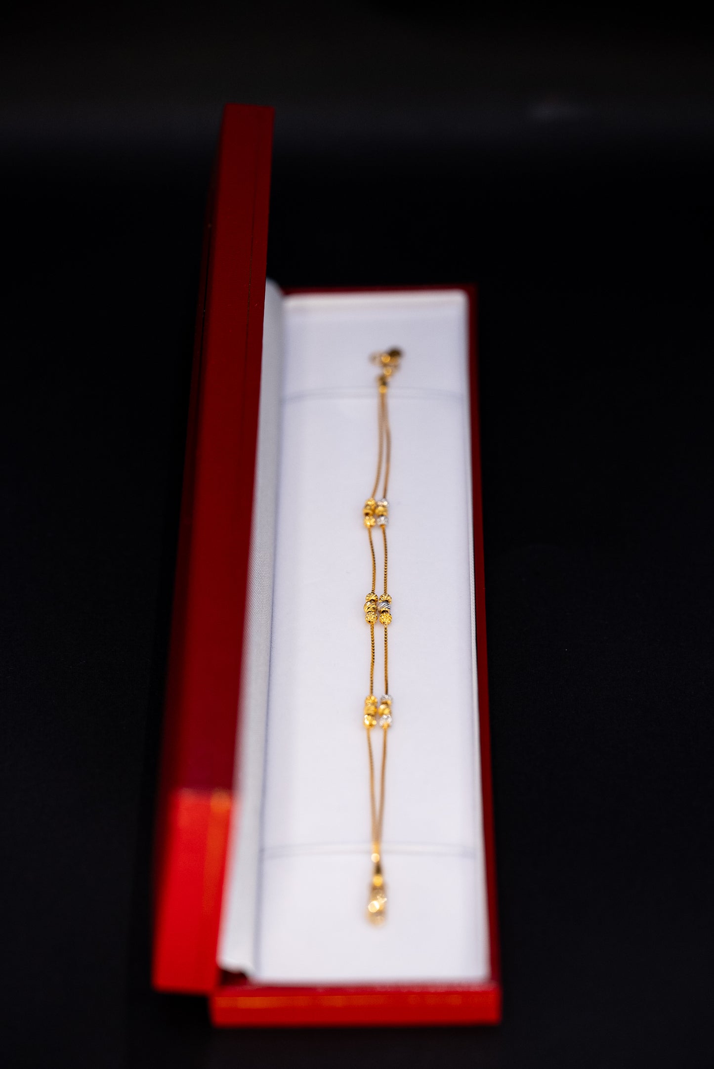Gold bracelet in a red box on a black background