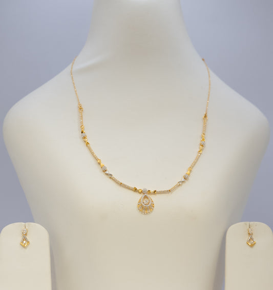 Gold necklace and earrings on a mannequin bust with a plain background