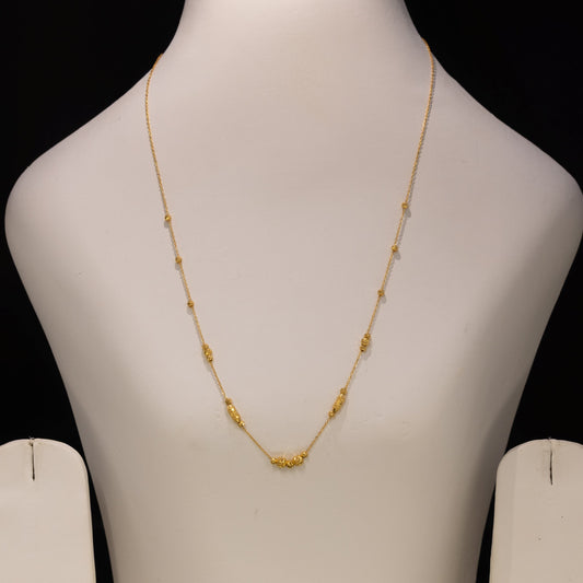 A delicate gold necklace displayed on a white jewelry bust against a black background.