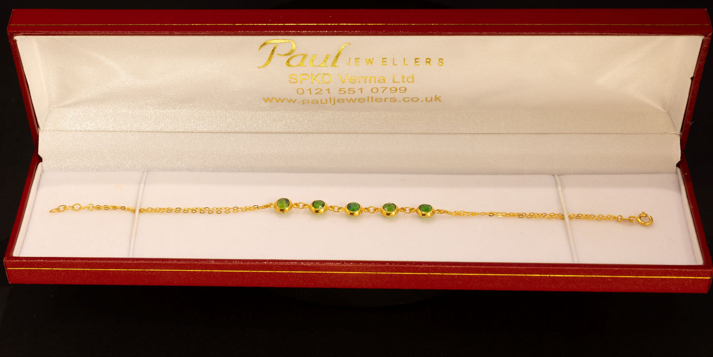 A delicate gold chain bracelet with three small green bead accents, presented inside an open red jewelry box with a white interior. The brand name 'Paul Jewellers' is visible on the inside lid.