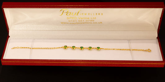 A delicate gold chain bracelet with three small green bead accents, presented inside an open red jewelry box with a white interior. The brand name 'Paul Jewellers' is visible on the inside lid.