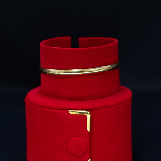 A red velvet jewelry display stand with gold-tone metal accents, including a small ring holder on the upper tier and a decorative bracket on the lower tier, set against a dark background.