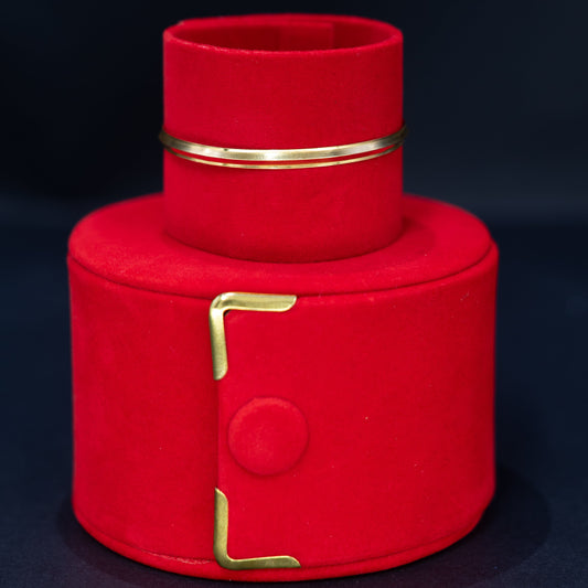 A red velvet jewelry box with gold-tone metal accents, shown open to reveal a matching red velvet ring holder inside, set against a dark background.