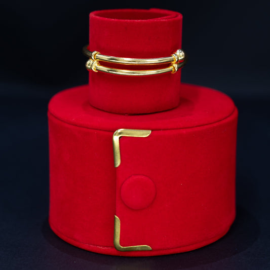 A adjustable baby bracelet displayed on a red cylindrical jewelry stand against a dark background.
