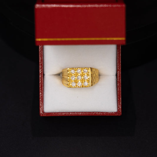A gold ring with a textured, grid-like pattern, presented inside an open red jewelry box with a white insert, set against a dark black background.