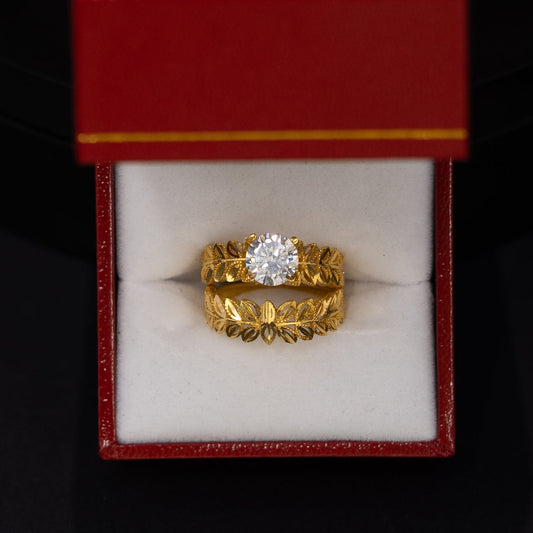 A yellow gold ring with a central clear gemstone displayed inside an open red jewelry box on a black background.